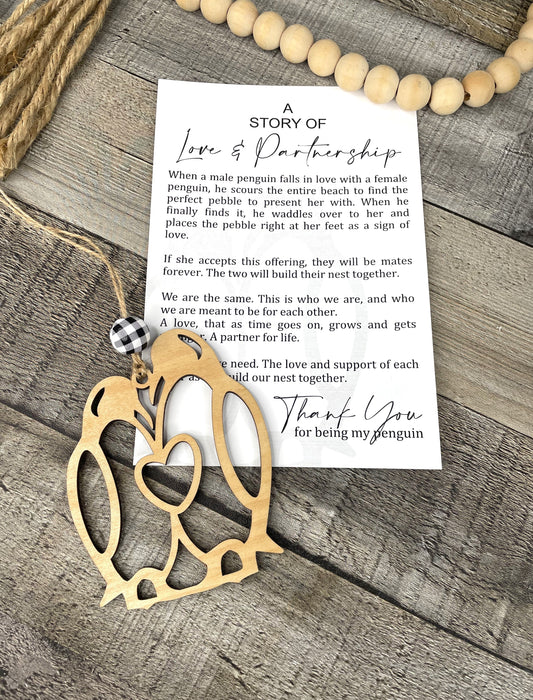 Wooden penguin ornament with a card on a wooden surface